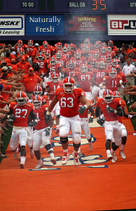 Clemson Tigers football team running in front of cheering fans.