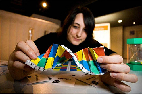 Photo of a young woman holding brightly colored, twisted paper up to the camera, 
