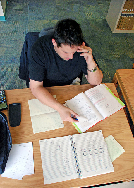 Photo looking down on a man studying at a desk in a library