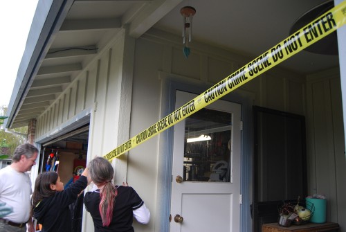 People placing crime scene tape around a house.