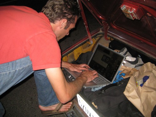 A man leaning over a laptop, typing is pictured here.