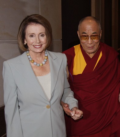 The photo shows, left, House Minority Leader Nancy Pelosi, dressed in a gray suit, holding hands with, right, Dalai Lama Tenzin Gyatso, dressed in maroon and yellow robes.