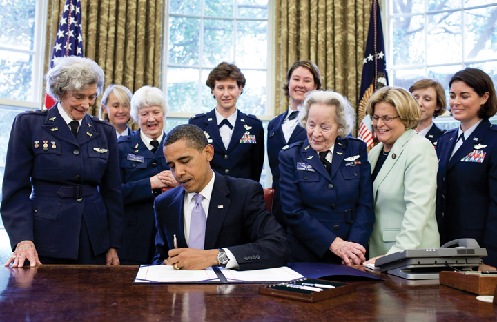 Photo of Barack Obama signing S.614 in the Oval Office July 1 at the White House. Also in the photo are Rep. Ileana Ros-Lehtinen, Women’s Airforce Service Pilots Elaine Danforth Harmon, Lorraine Z. Rodgers and Bernice Falk Haydu, and active duty USAF pilots Colonel Dawn Dunlop, Colonel Bobbi Doorenbos, Lieutenant Colonel Wendy Wasik, Major Kara Sandifur and Major Nicole Malachowski (former Thunderbird pilot).