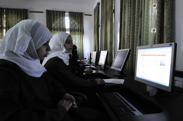 Two girls in headscarves working on computers