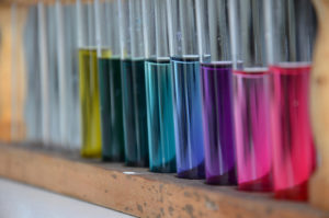 Row of metallic rainbow-colored tubes with silver tops
