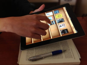 hand holding an iPad with book covers on its screen