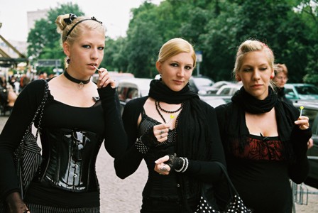Photo of three young women dressed in Goth outfits walking outside in a city.