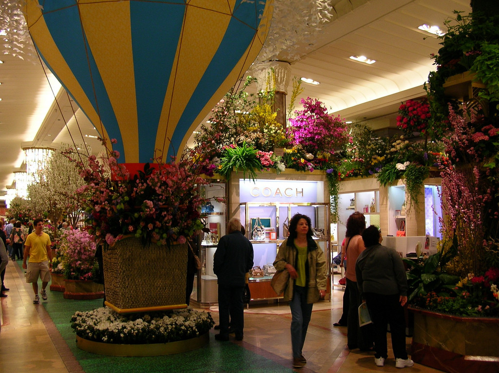 Photo of main floor of Macy's department store, decorated with flowers and a large hot-air balloon. Several shoppers are seen.