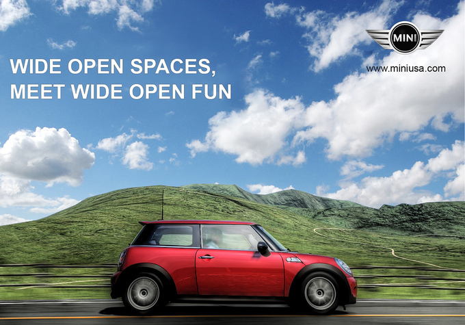 A Mini car drives down a road on a beautiful sunny day by some scenic hills. Text says Wide Open Spaces, Meet Wide Open Fun.