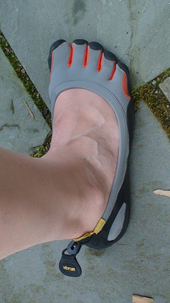 Photo of a man's leg and foot. He's wearing a gray Five Fingers shoe, which 