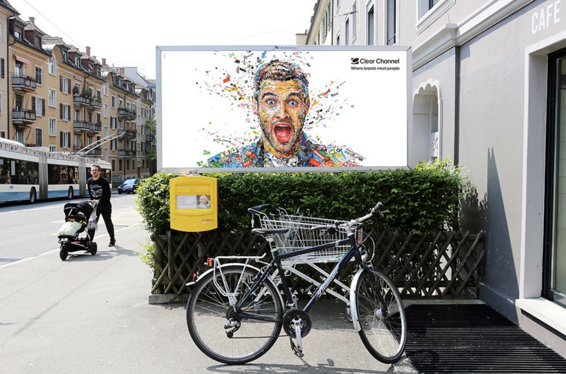 A billboard for ClearChannel. It depicts a bright and colorful mosaic that forms a portrait of an excited man.