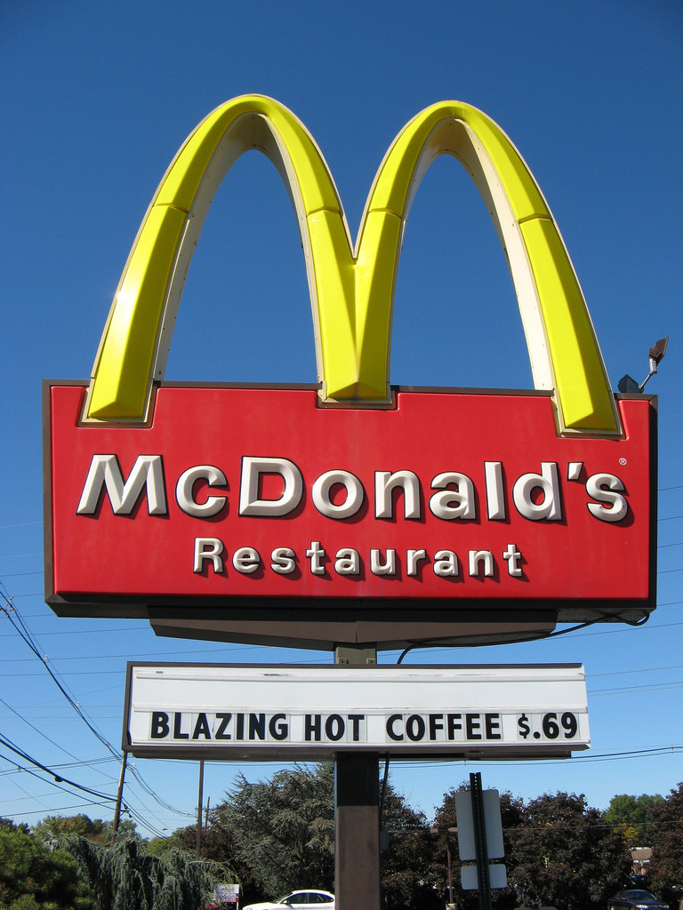 Photo of McDonald's Restaurant sign (with the famous golden arches) that reads underneath,