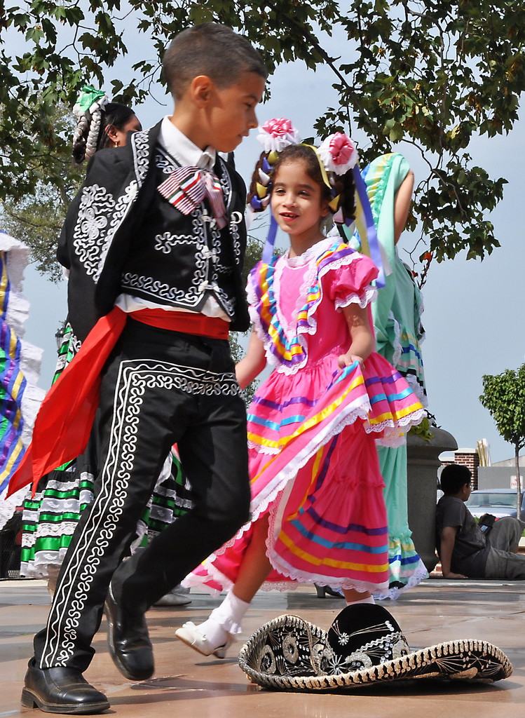 A young Mexican boy and girl dressed in fancy traditional costumes dance.