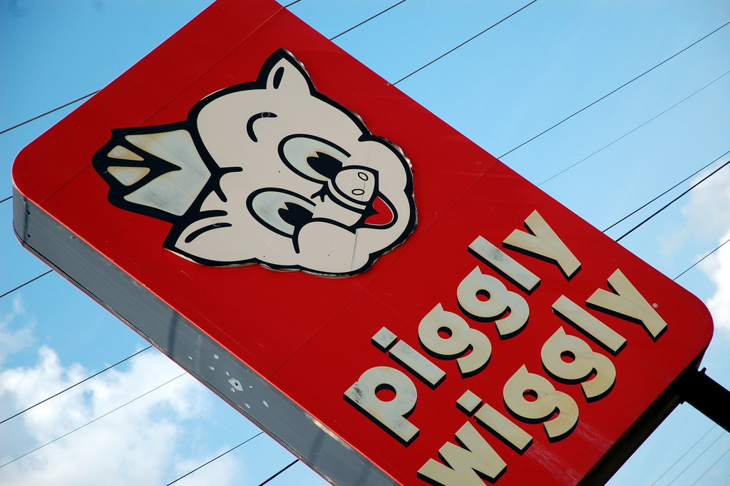 A sign that says Piggly Wiggly and features a cartoon image of a pig's face.