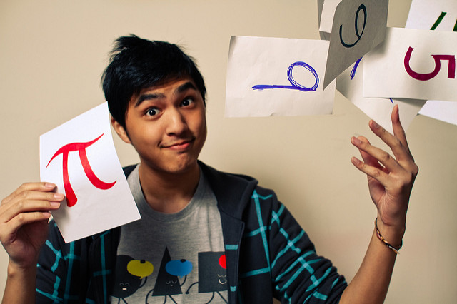 Young man holding a page with a red pi symbol in one hand, and tossing pages with numbers on them from the other hand