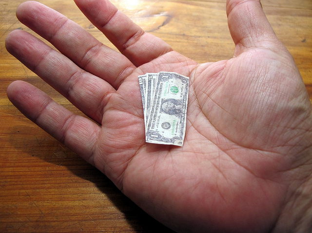 Open palm holding miniature dollar bills