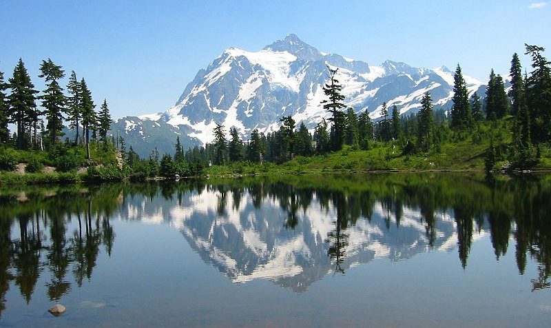 A mountain peak reflected in a lake surrounded by trees