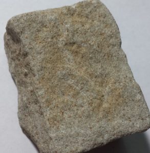 A light-colored mineral with straight surfaces and a somewhat rough texture