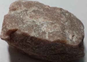 A slightly pink mineral with a deep white vein
