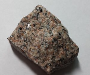 A light pinkish mineral with flecks of gray, black, and white