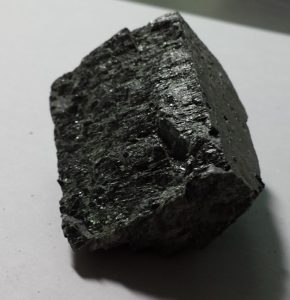 A dark, slightly shiny mineral with straight sides and straight cleavage marks