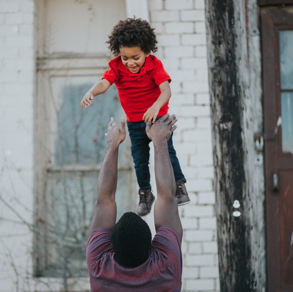 A father playfully tossing his young child, as he stands ready to catch them.