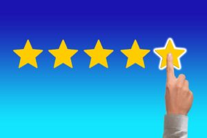 Five gold stars on a blue background with a hand pointing and touching the fifth star.