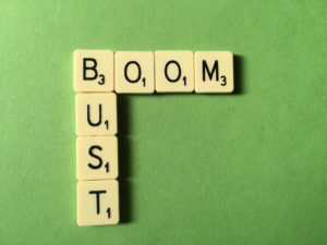 Scrabble tiles spell the words BOOM and BUST; green background