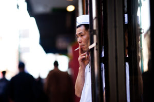 A cook pokes his head out out of a doorway for a smoke break.