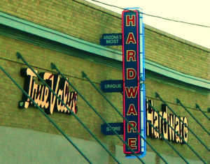 Photo of a True Value Hardware store sign on the side of a brick building, with additional signage that reads, 