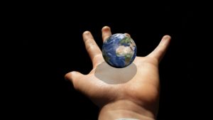 Picture of a tiny globe hovering above a child's outstretched hand.