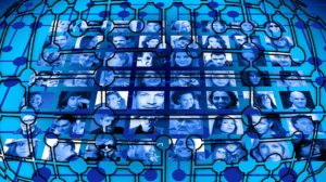 Images shows the faint lines of an organizational chart superimposed on a collage of photos showing different people. The work resembles a stained-glass window, with backlit blue and black shapes.