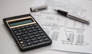 Photo of a calculator, pen, and a budget sheet on a desk