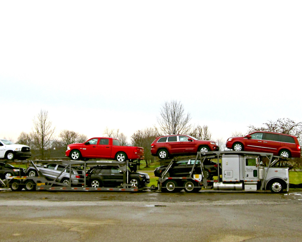 Large truck loaded with new cars.