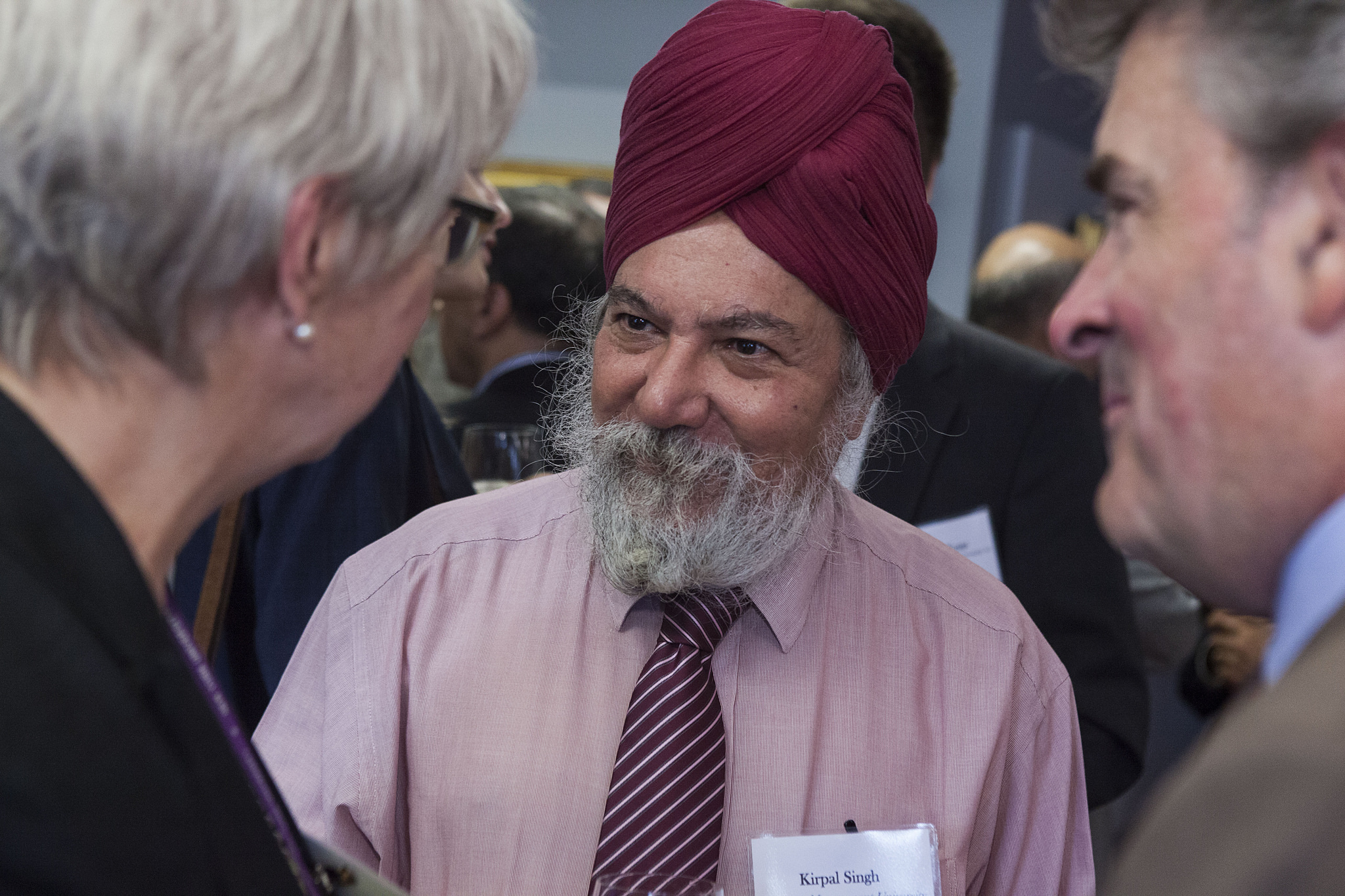 Photo of two men and one woman in a business setting. One man wears a turban.