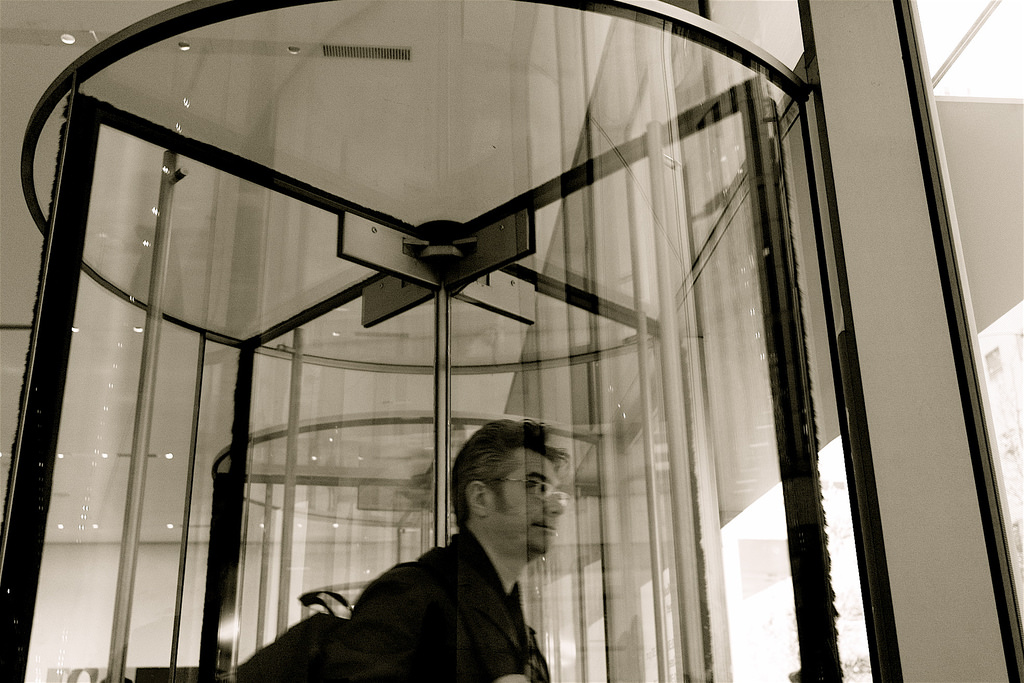 Photo of man exiting building through a revolving glass door at MOMA