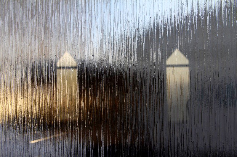 Photo collage showing two pale towers viewed through a rainy window