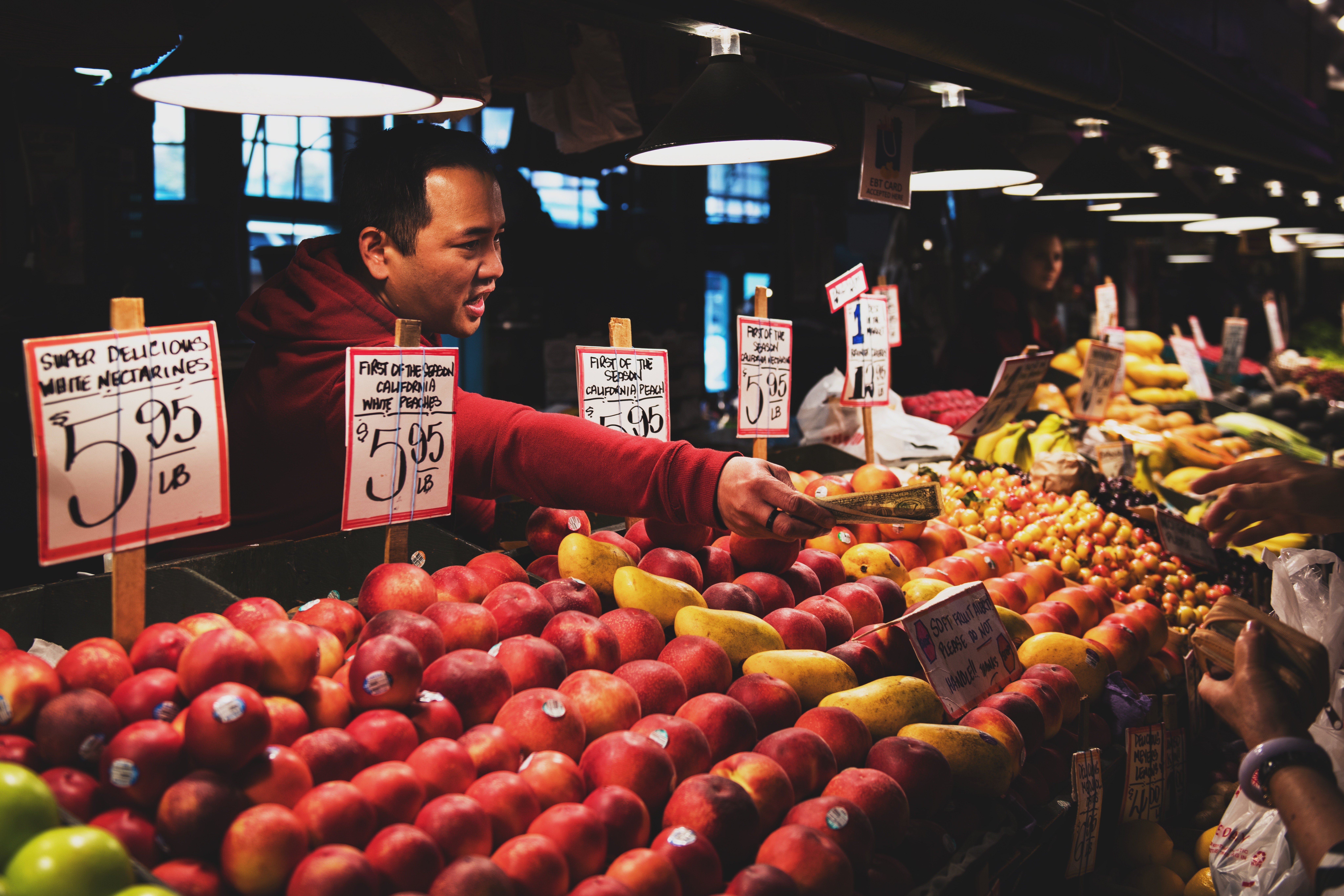 Photograph of a man returning some change after someone has purchased fruit from his fruit stand.
