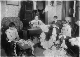 Black-and-white photo showing a family of four sitting in a parlor or living room sewing doll clothes.