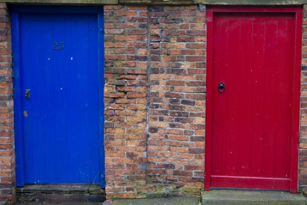 Photo of two doors, one painted bright blue, the other painted red.