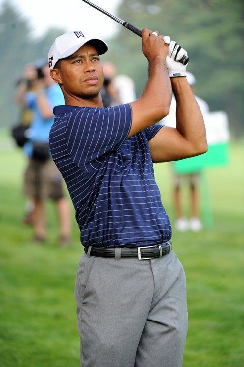 A photo of golfer Tiger Woods holding his golf club up in the air on the golf course.