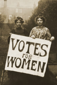 Black and white photograph of two female suffragettes holding a poster saying 