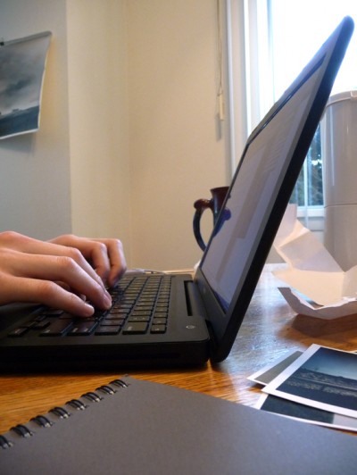 A person is shown from the side, typing on a laptop.