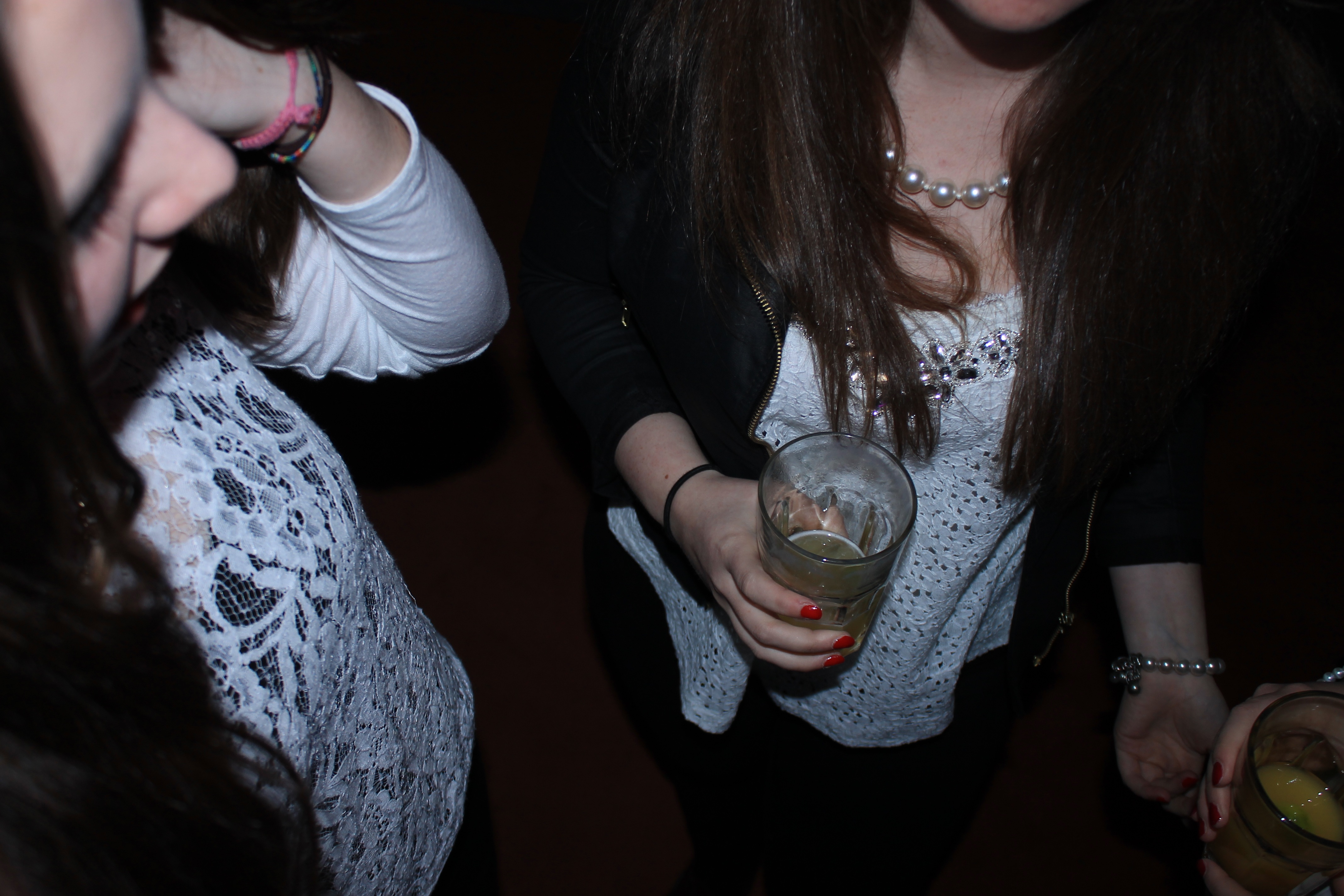 Teen girls holding drinks at a party.