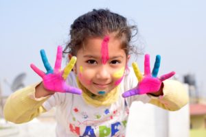 A girl with outstretched hands painted with different bright colors