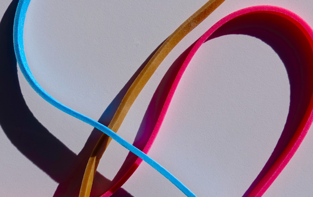 Close-up of three brightly colored rubber bands (blue, gold, and red).