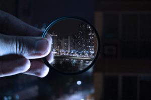 Magnifying glass showing a city scene through the glass.