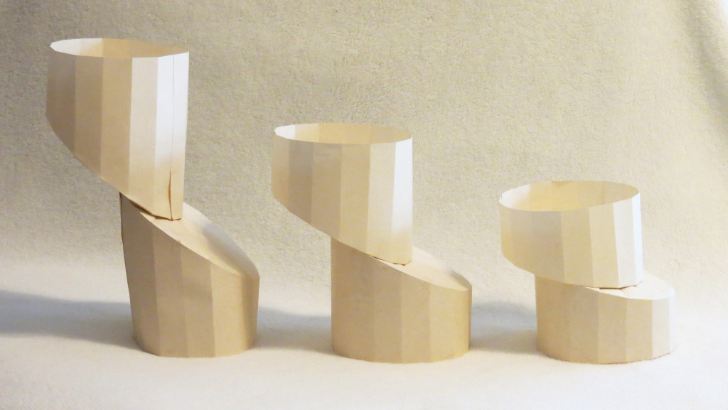 Three paper cylinders. The top of each has been diagonally cut and shifted slightly to the left.