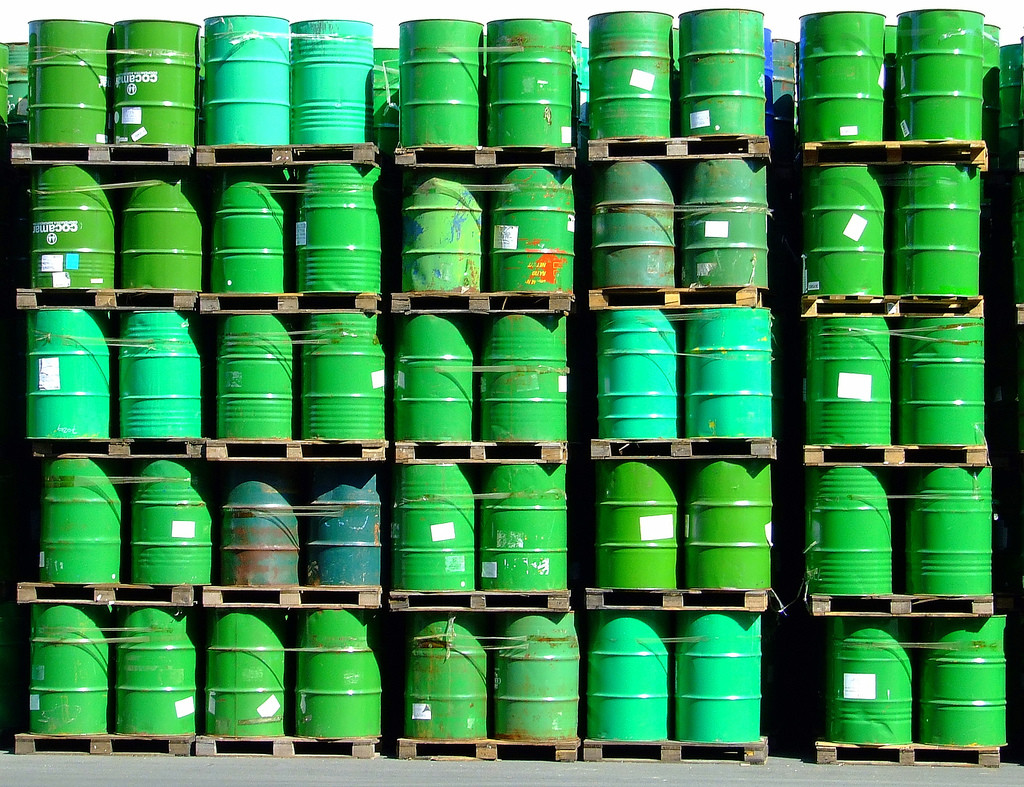 Five stacked rows of green-colored oil barrels.