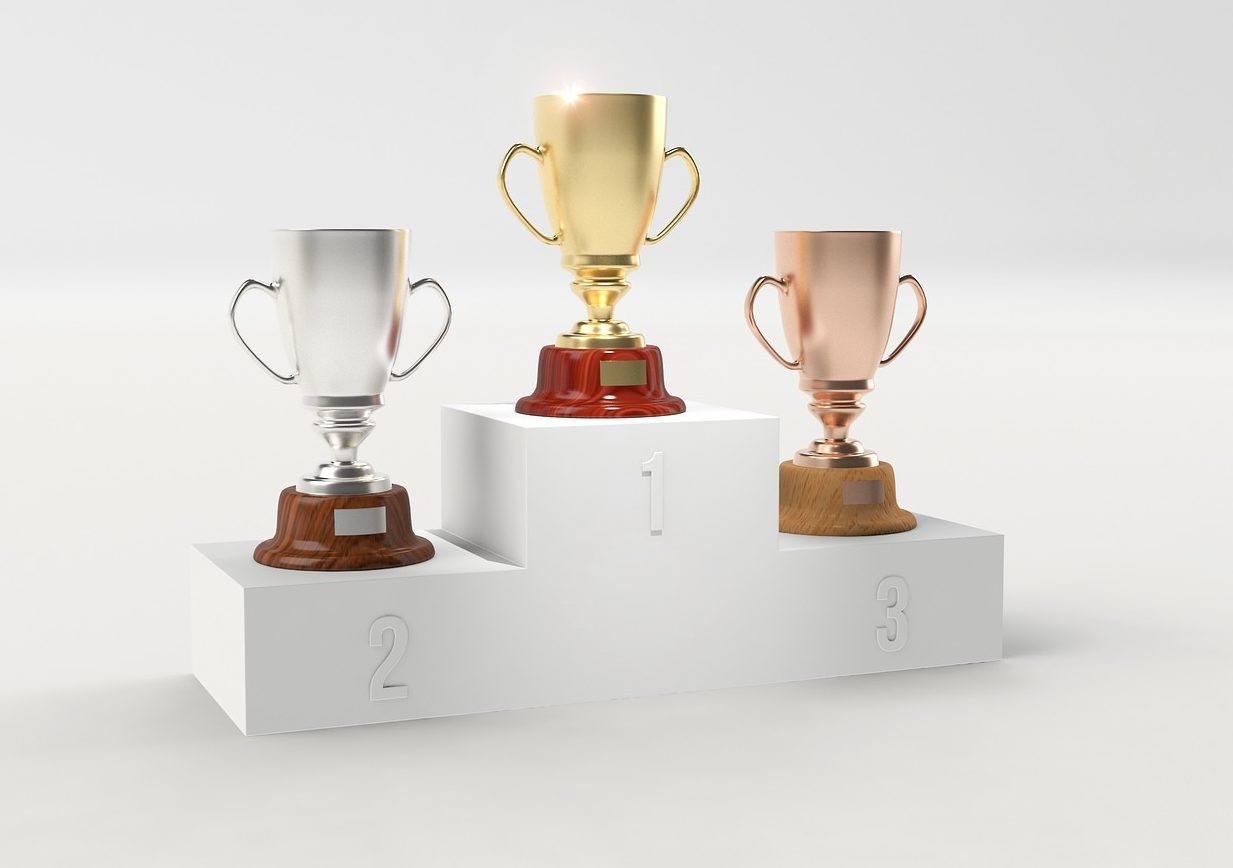 Image of gold, silver, and copper trophies set on risers indicating first, second, and third place.
